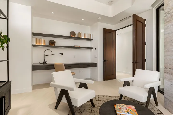 Recessed lighting illumination, wall-mounted desk with built-in drawers, floating shelving with integrated lighting, wood-finish flooring, and dark wood doors with dark hardware