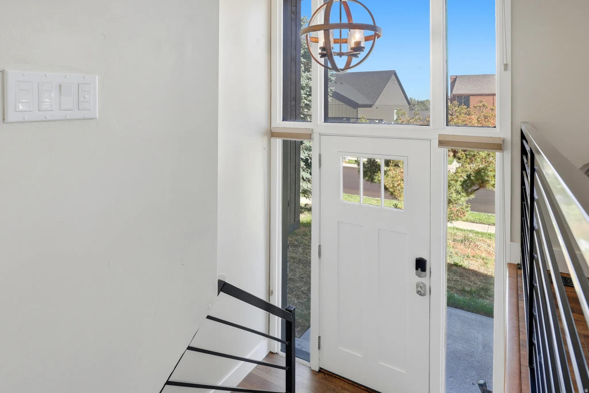 White entry door with multi-pane window, adjacent full-length side windows, and transom windows