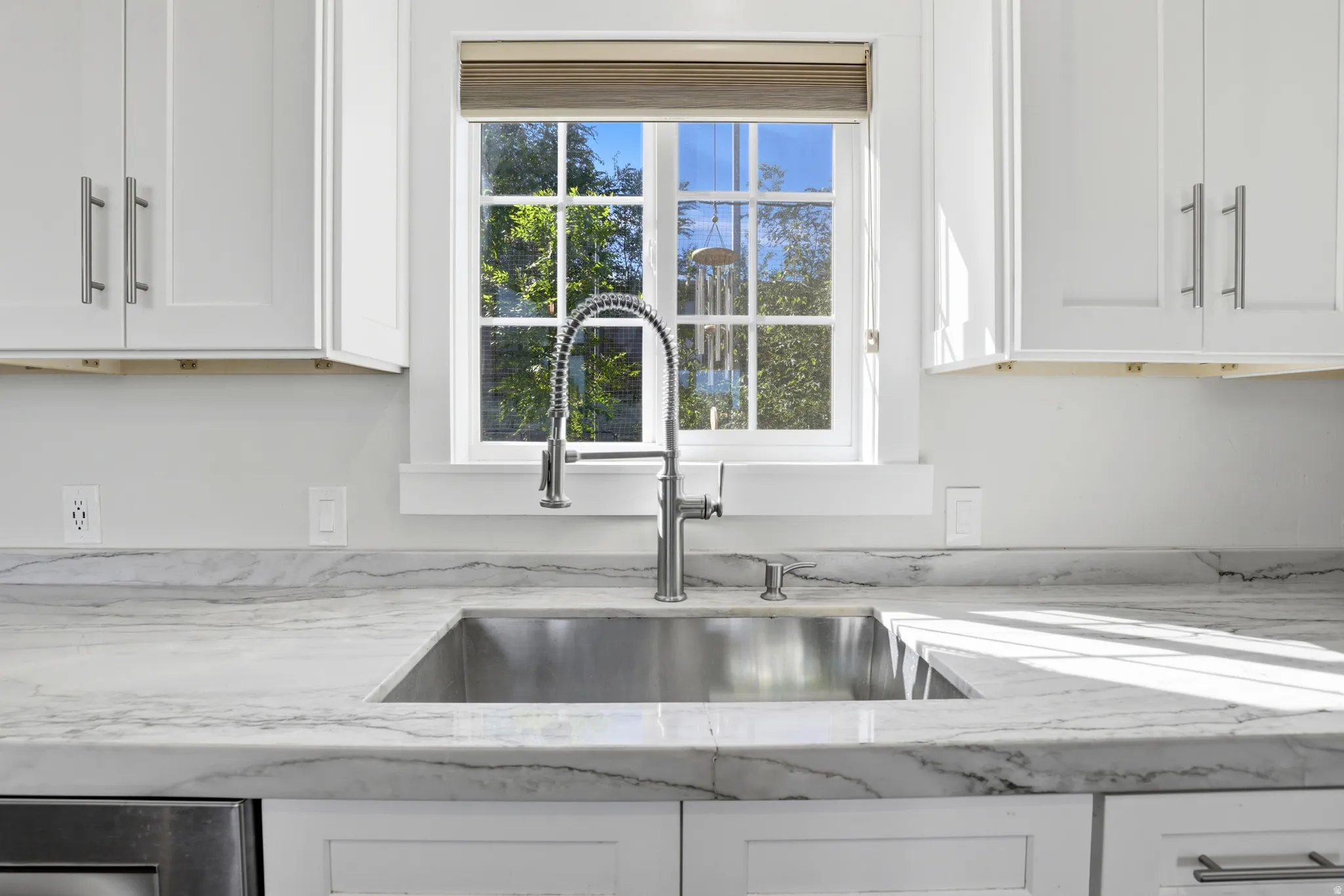 White shaker cabinetry with brushed nickel hardware, undermount stainless steel sink, gooseneck faucet, and stone countertops