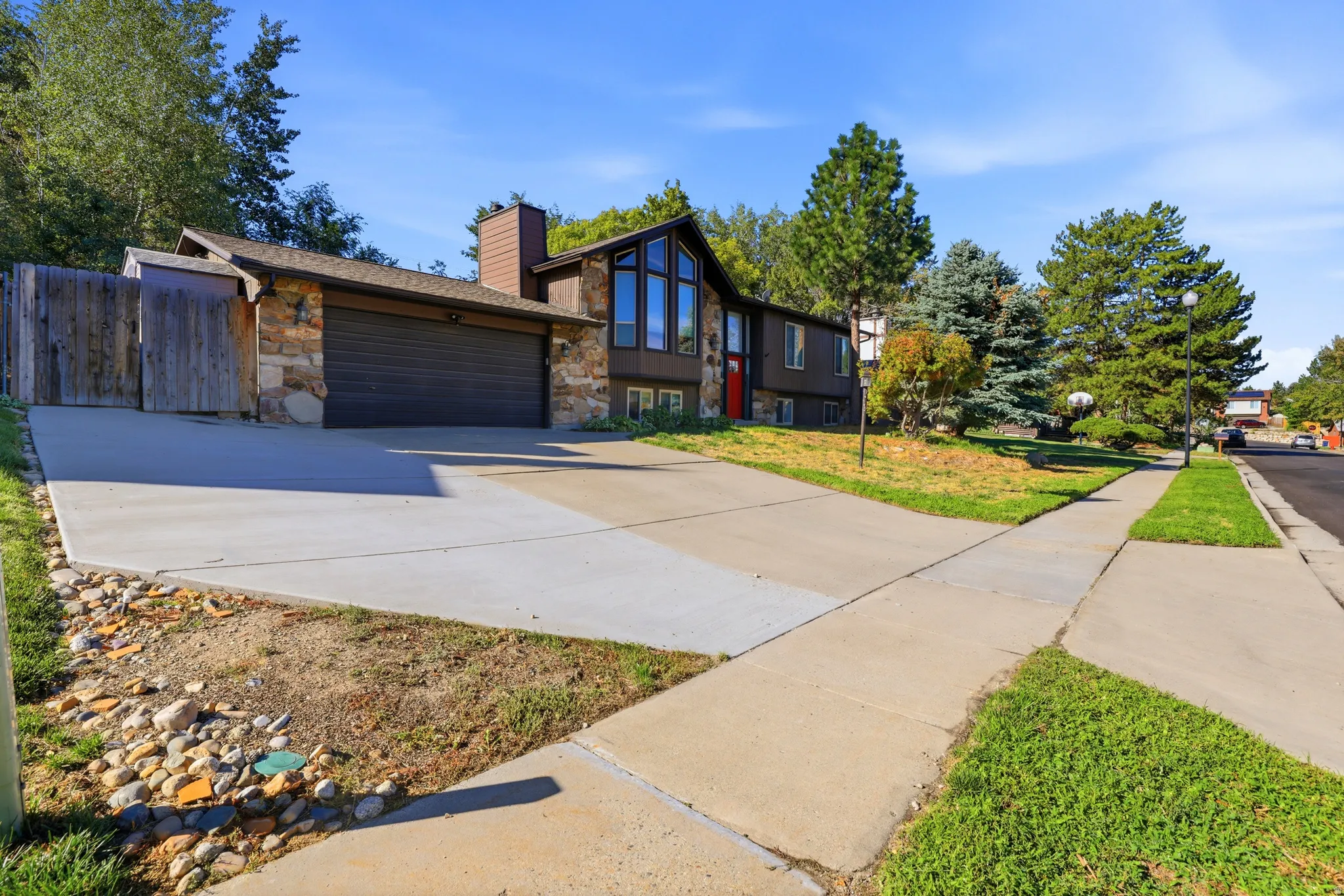 Contemporary-style exterior with stone and wood siding, prominent multi-pane windows, attached garage, and concrete driveway