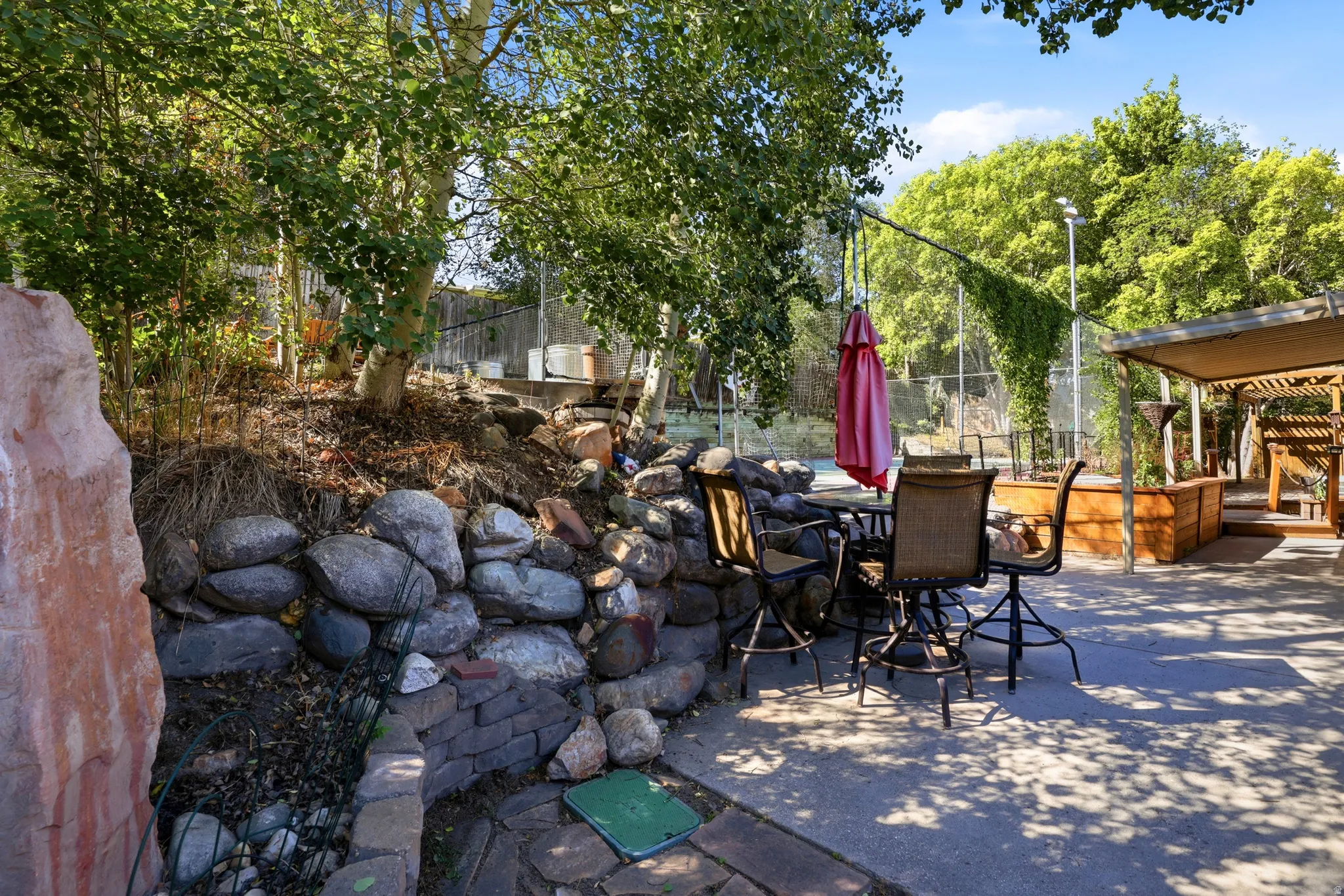 Expansive patio featuring a built-in pergola, raised garden beds, and stone retaining walls
