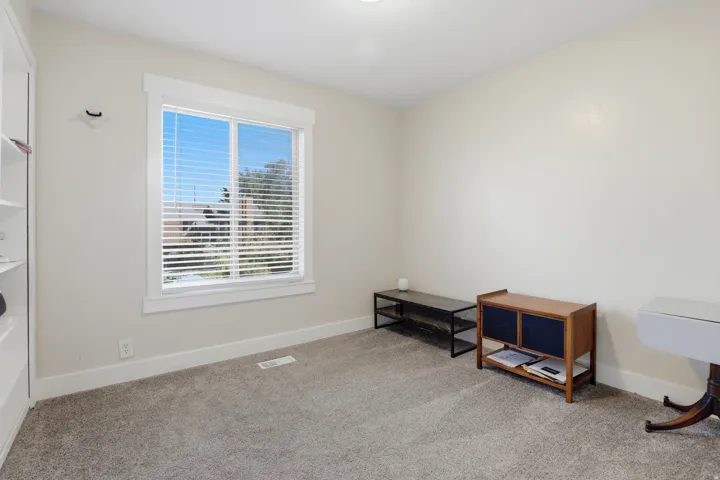 Built-in shelving unit, neutral wall finish, carpeted flooring, and a window with blinds