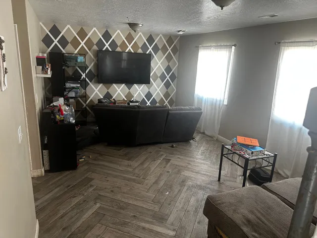 Herringbone pattern wood-finish flooring with a decorative accent wall and window treatments