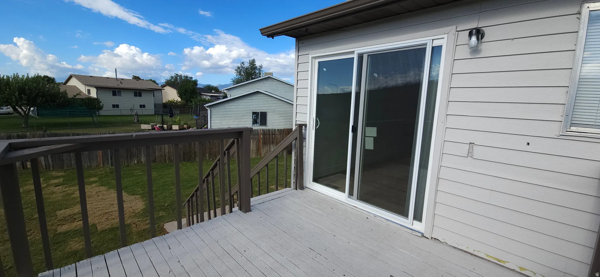 Outdoor deck with wood-finish railing, sliding glass door, and exterior wall siding