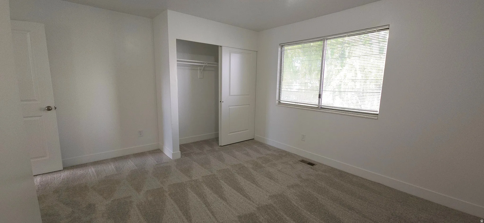 Recessed closet with built-in shelving, white trim, and light gray patterned carpeting