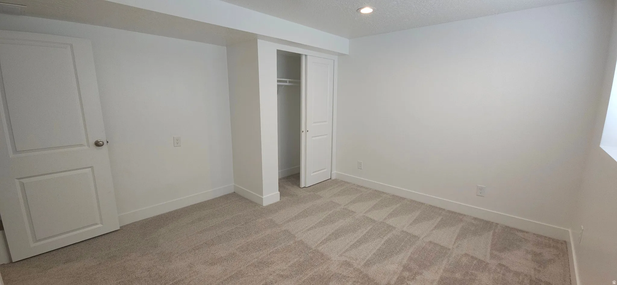 Neutral tone carpeting with geometric pattern, white walls, and recessed lighting