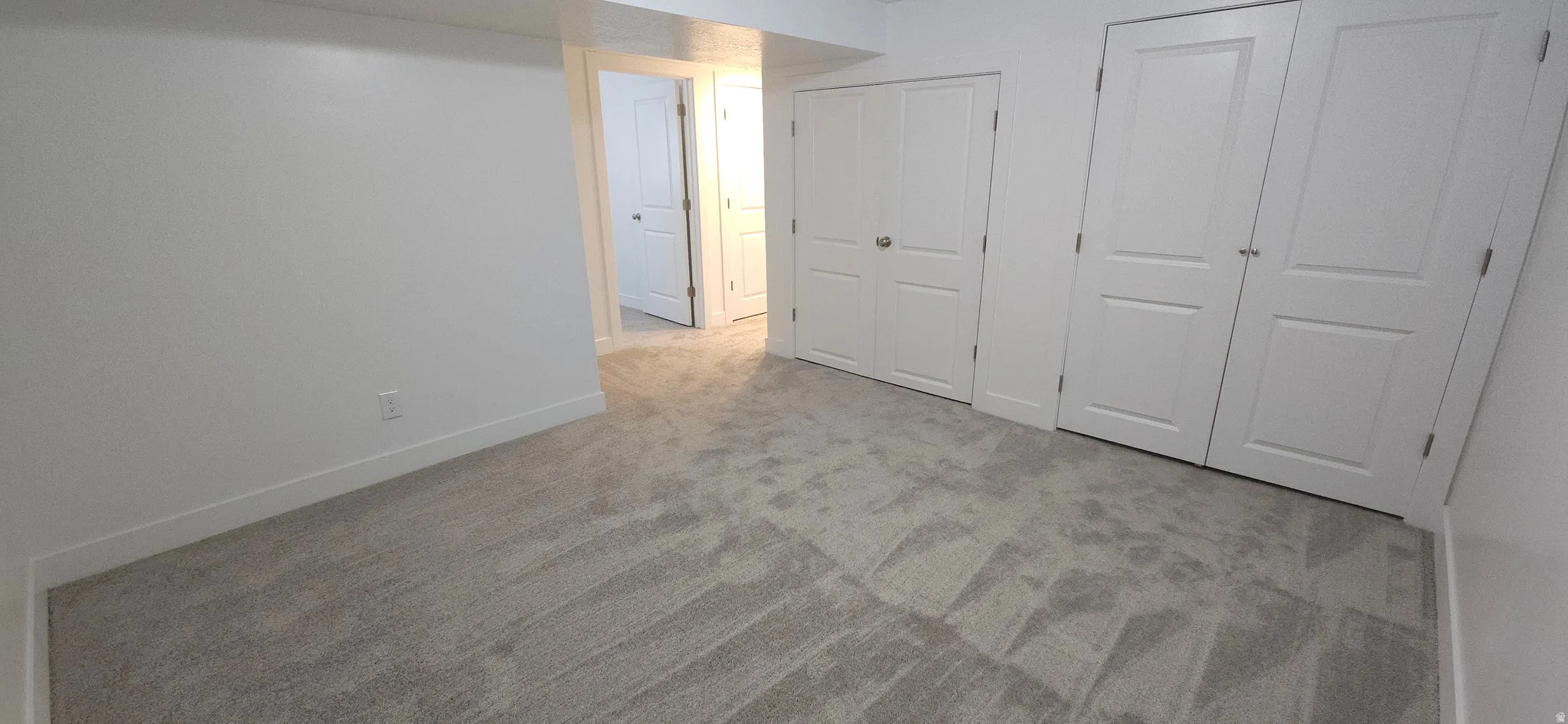 Light-toned carpeting, white walls, and white interior doors