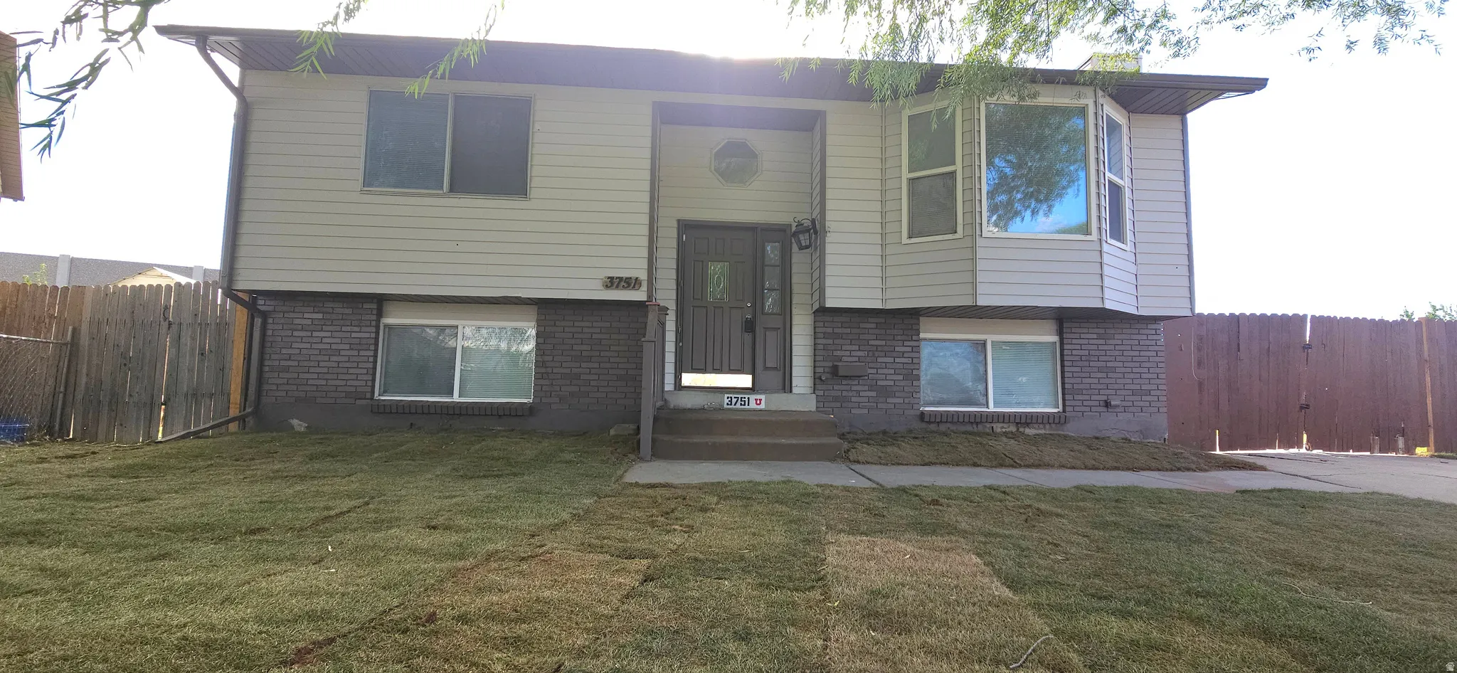 Split-level residence featuring a bay window, brick and siding exterior, front entry with storm door, and a newly laid lawn
