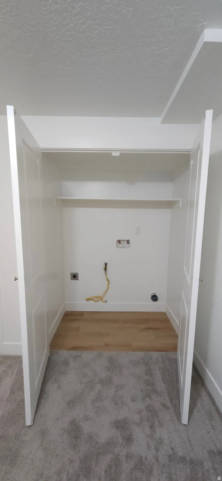 Utility closet with wood-finish flooring, shelving, and bifold doors