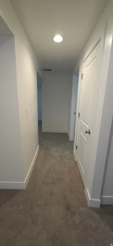 Neutral tone carpeting with white trim and recessed lighting