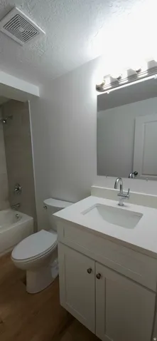 White vanity with cabinet storage, integrated sink, and chrome faucet
