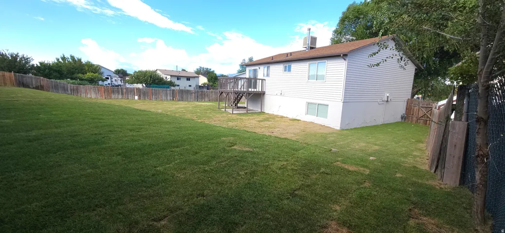 Expansive backyard featuring a wood privacy fence, a multi-level deck, and light-colored siding