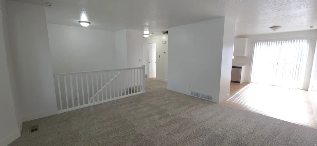 Carpeted living area with white baluster railing and neutral wall finishes