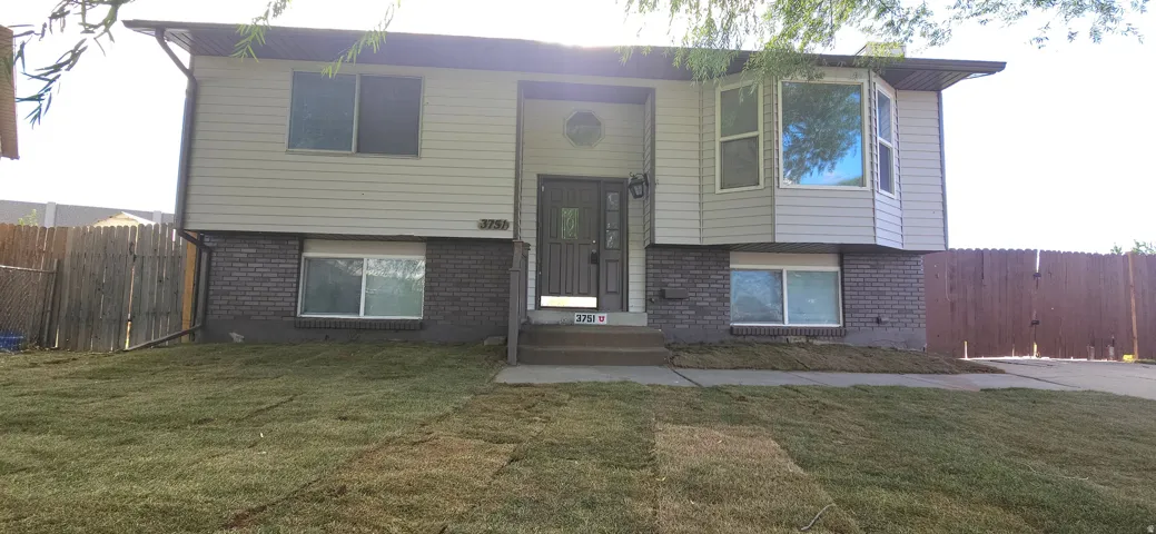Split-level residence featuring a bay window, brick and siding exterior, front entry with storm door, and a newly laid lawn