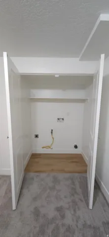 Utility closet with wood-finish flooring, shelving, and bifold doors