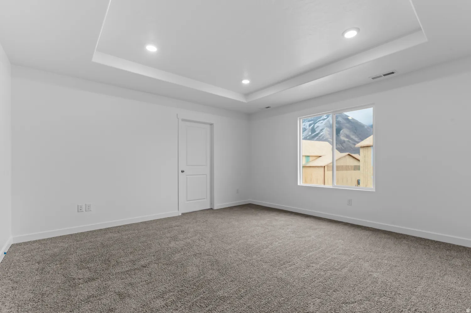 Tray ceiling with recessed lighting, wall-to-wall carpeting, and a window with mountain scenery