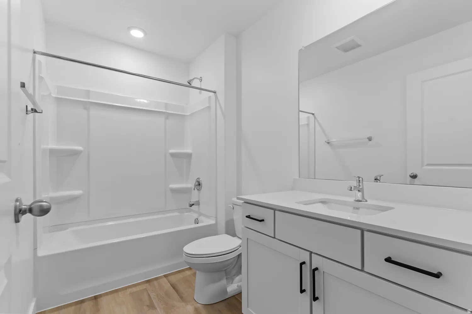 Bathroom featuring a built-in tub and shower combination, a single vanity with a white countertop, and wood-finish flooring