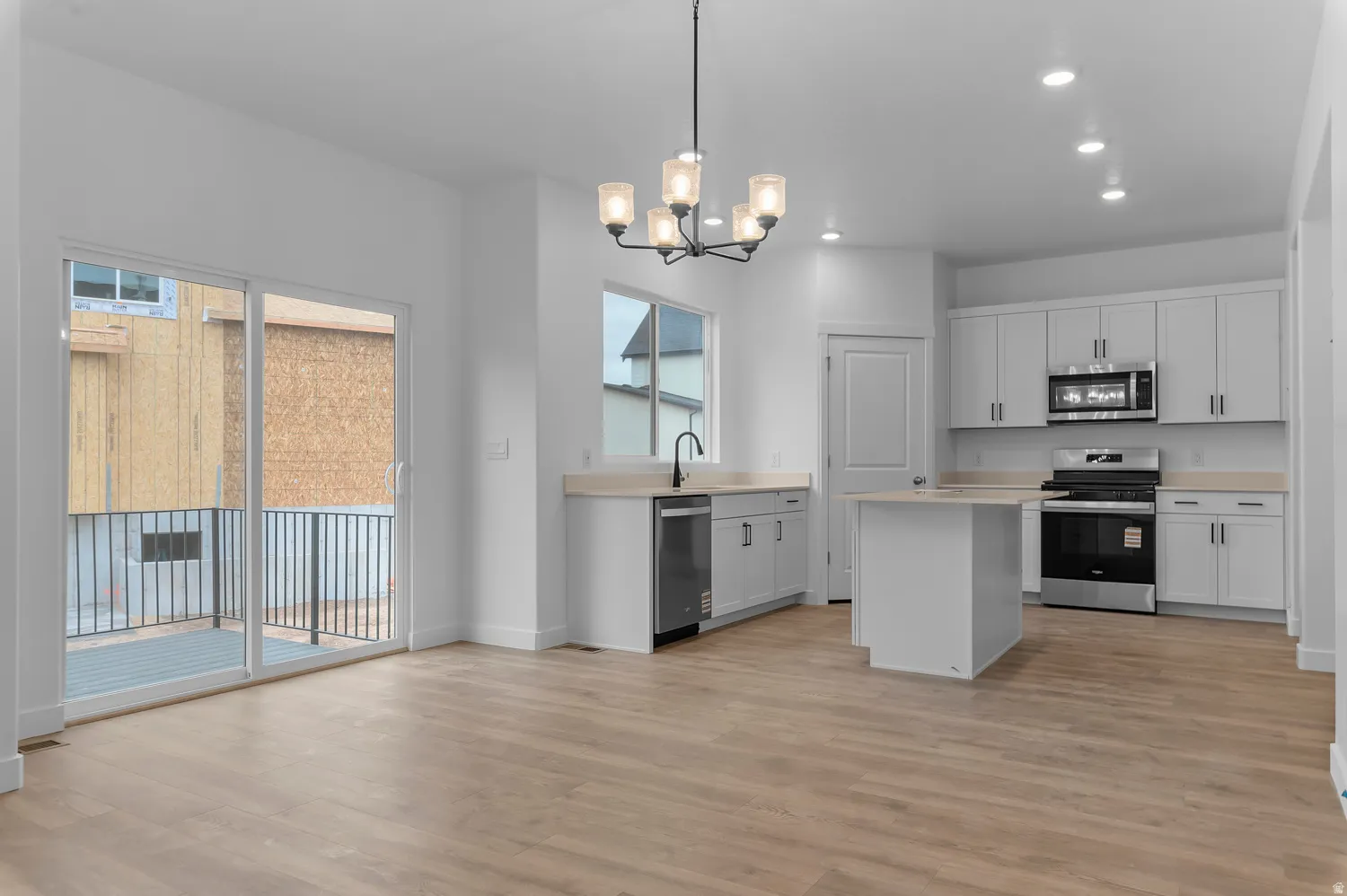 Modern kitchen with white cabinetry, stainless steel appliances, and a central island