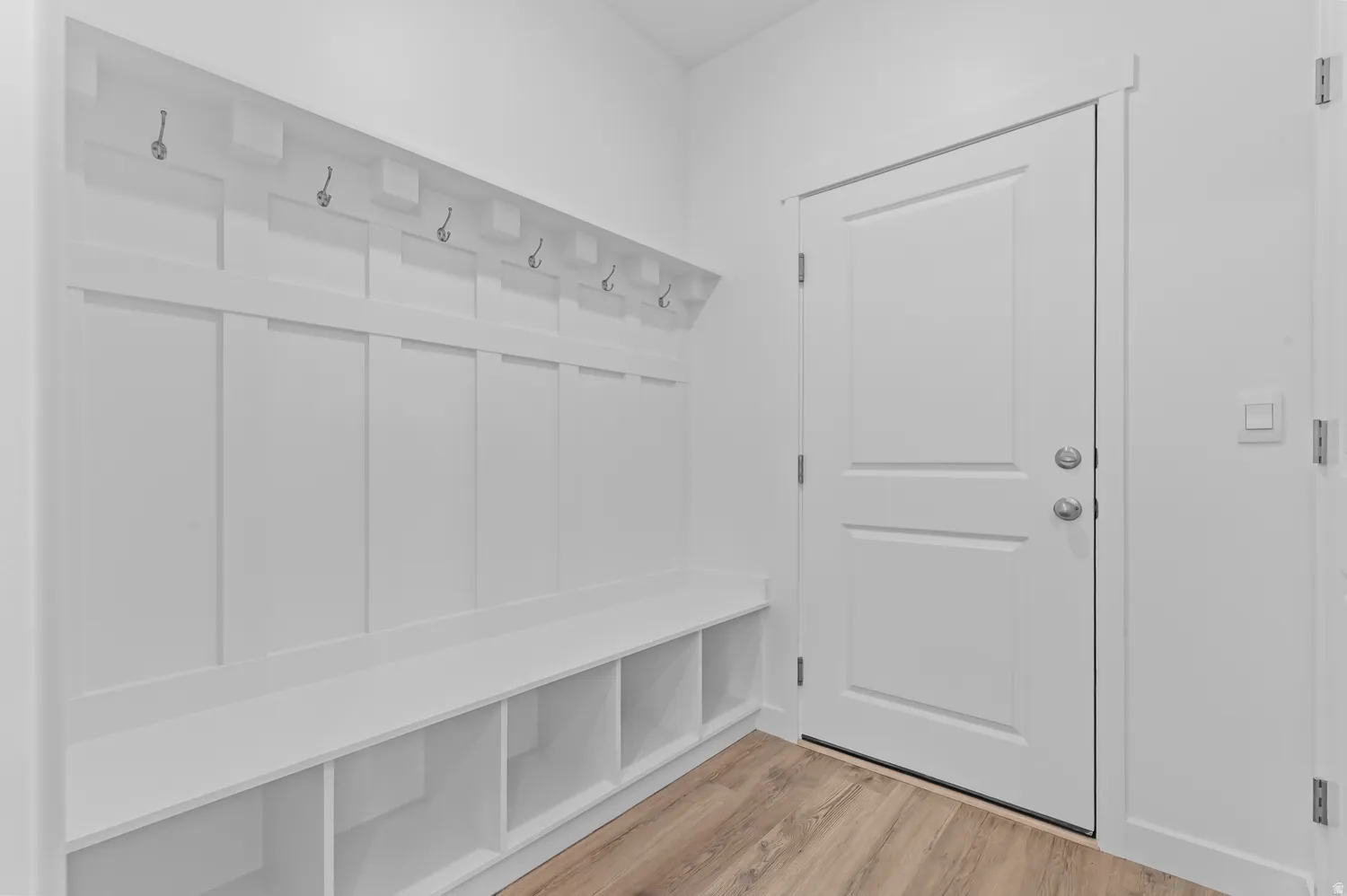 Entryway featuring a built-in bench with integrated cubbies, white board and batten wall treatment, and coat hooks