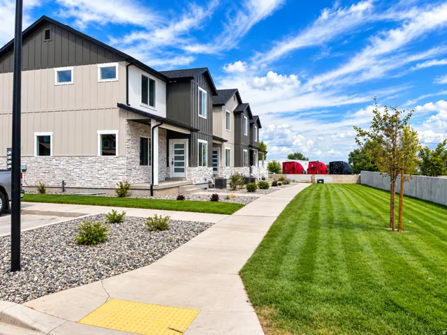 Modern townhome facade featuring vertical siding, stone veneer accents, and a covered entry
