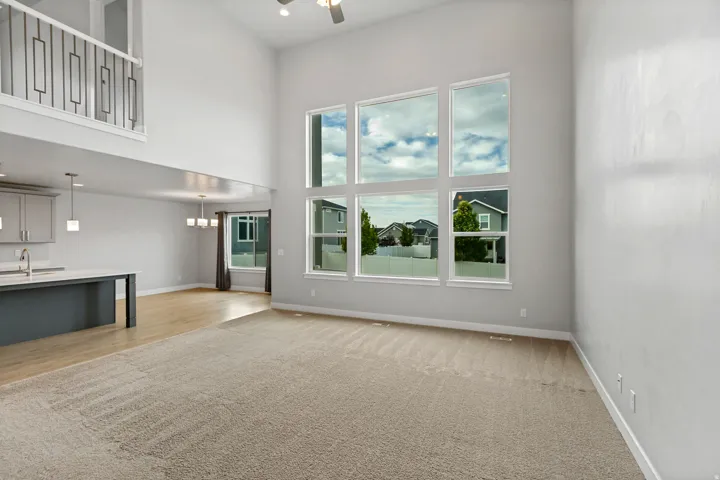 Vaulted ceiling with a ceiling fan, a large window array, and a carpeted floor