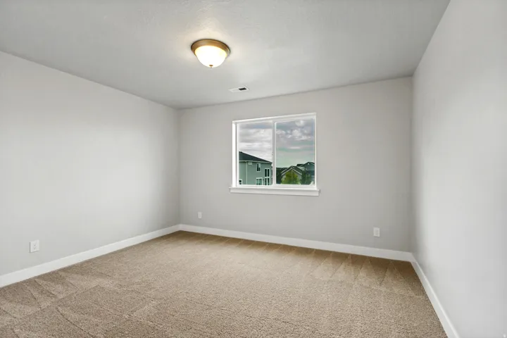 Neutral wall finishes, carpeted flooring, and a single window with white trim