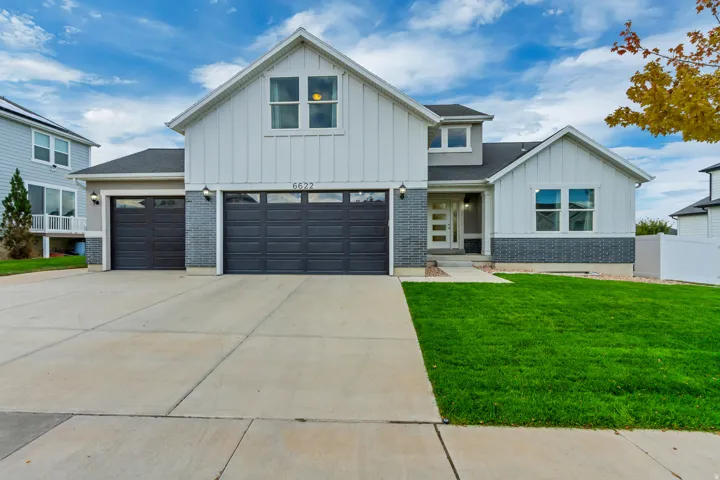 Contemporary exterior with vertical siding, stone accents, a multi-pane front door, and a three-car garage