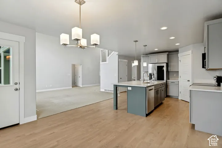 Open-concept kitchen and living area with wood-finish flooring, recessed lighting, and a kitchen island with pendant lighting