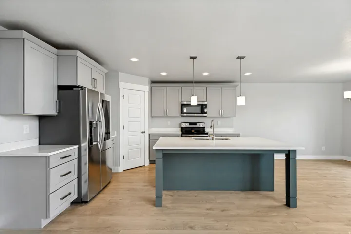 Kitchen featuring light gray cabinetry, stainless steel appliances, a center island with pendant lighting, and wood-finish flooring
