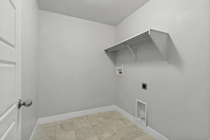Laundry room featuring a built-in shelf with hanging rod and tile flooring