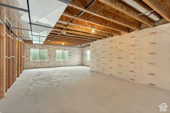 Unfinished basement featuring exposed wood framing, concrete flooring, and multiple windows