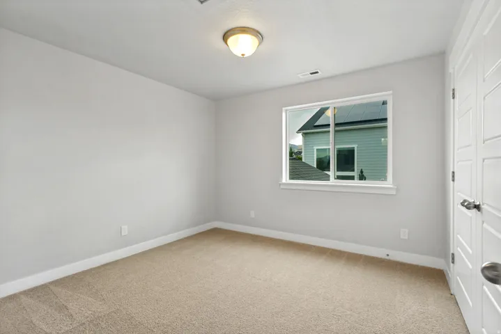 Neutral wall color, carpeted flooring, single window, flush mount lighting, and white paneled doors