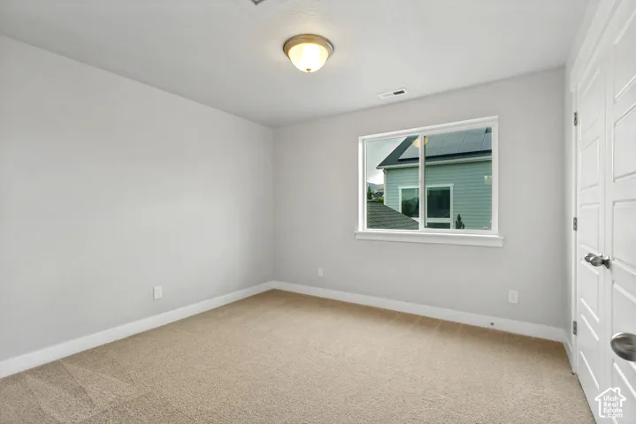 Neutral wall color, carpeted flooring, single window, flush mount lighting, and white paneled doors