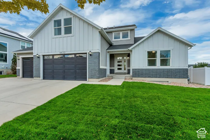 Contemporary residence featuring a two-car garage, front-facing gables, and a prominent front door with vertical window panels