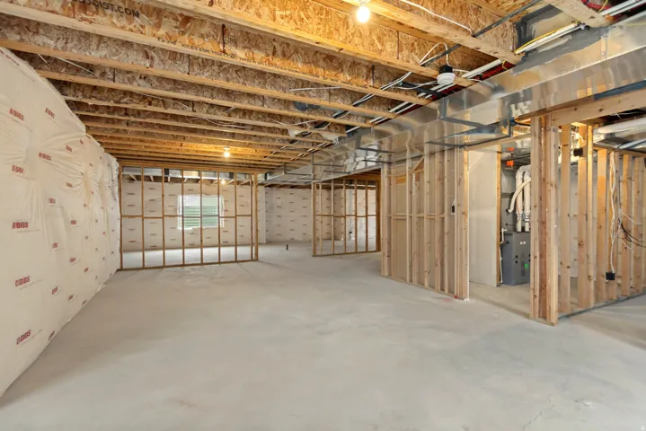 Unfinished basement featuring exposed wood joists, framed walls, and concrete flooring