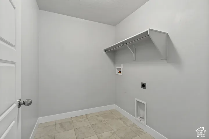 Laundry room featuring a built-in shelf with hanging rod and tile flooring
