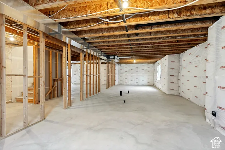 Unfinished basement featuring concrete flooring, exposed wooden joists, framed walls, and metal ductwork