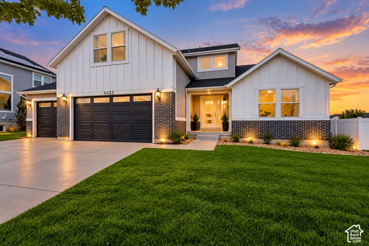 Contemporary exterior featuring vertical board-and-batten siding, dark brick masonry, a three-car garage, and a covered front porch entry