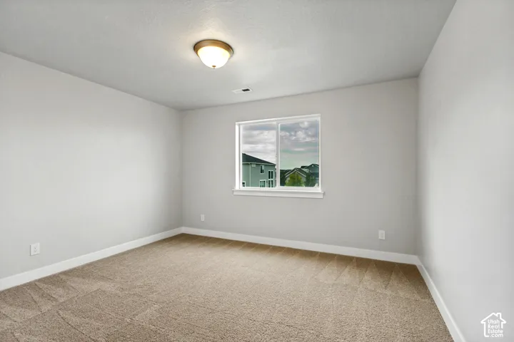 Neutral wall finishes, carpeted flooring, and a single window with white trim