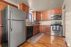 Kitchen featuring wood-finish flooring, wood cabinetry, stainless steel appliances, and a window above the sink