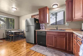 Wood-finish flooring, wood cabinetry, built-in dishwasher, and a stainless steel refrigerator