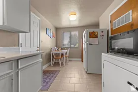 Kitchen area featuring light gray cabinetry, solid surface countertops, tile flooring, and a window
