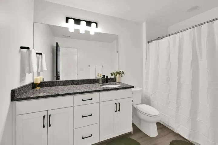 Vanity with black speckled countertop, undermount sink, and black hardware