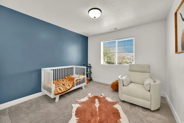 Recessed window with horizontal blinds, overhead flush mount lighting, textured carpet flooring, and a contrasting accent wall