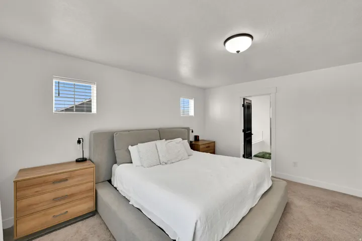 White walls with carpet flooring, recessed window with blinds, semi-flush mount ceiling light, and an open doorway