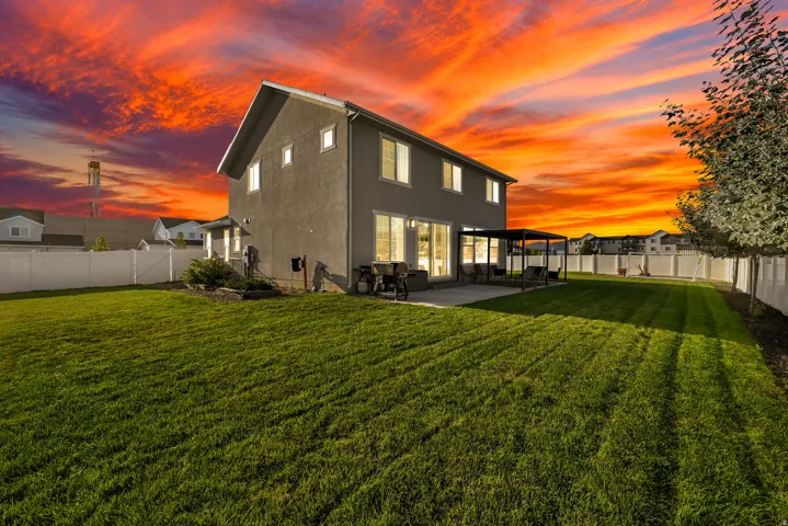 Expansive backyard featuring a manicured lawn, full privacy fencing, and a concrete patio with a metal pergola