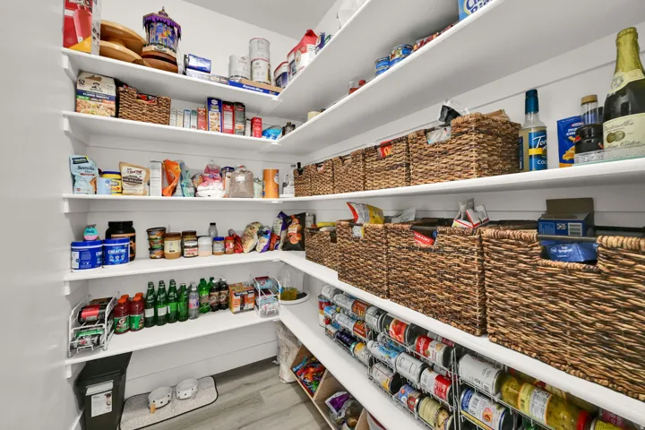 Walk-in pantry with extensive shelving, shiplap wall accents, and wood-finish flooring