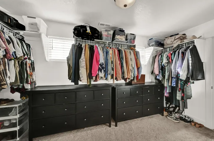 Recessed ceiling lighting illuminates the built-in shelving, hanging rods, and window with blinds