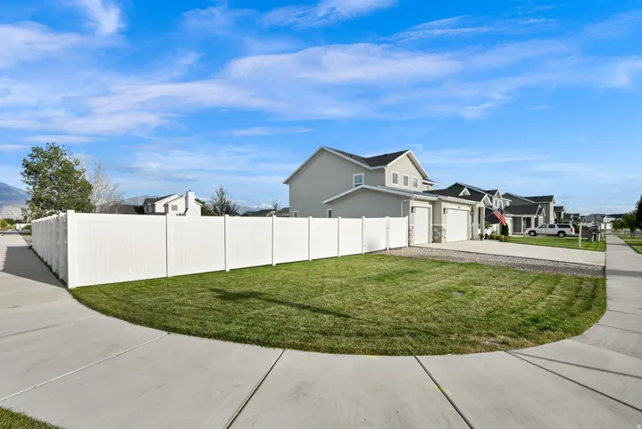 Two-story residence with a two-car garage, white vinyl fencing, and a concrete driveway