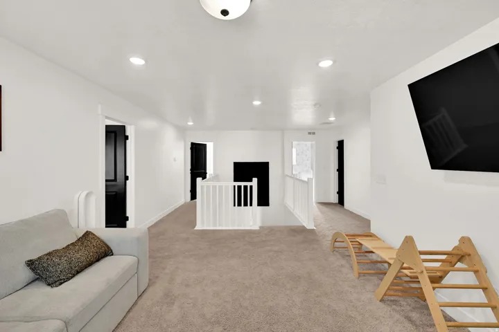 Carpeted area featuring recessed lighting, white walls, and a white staircase railing